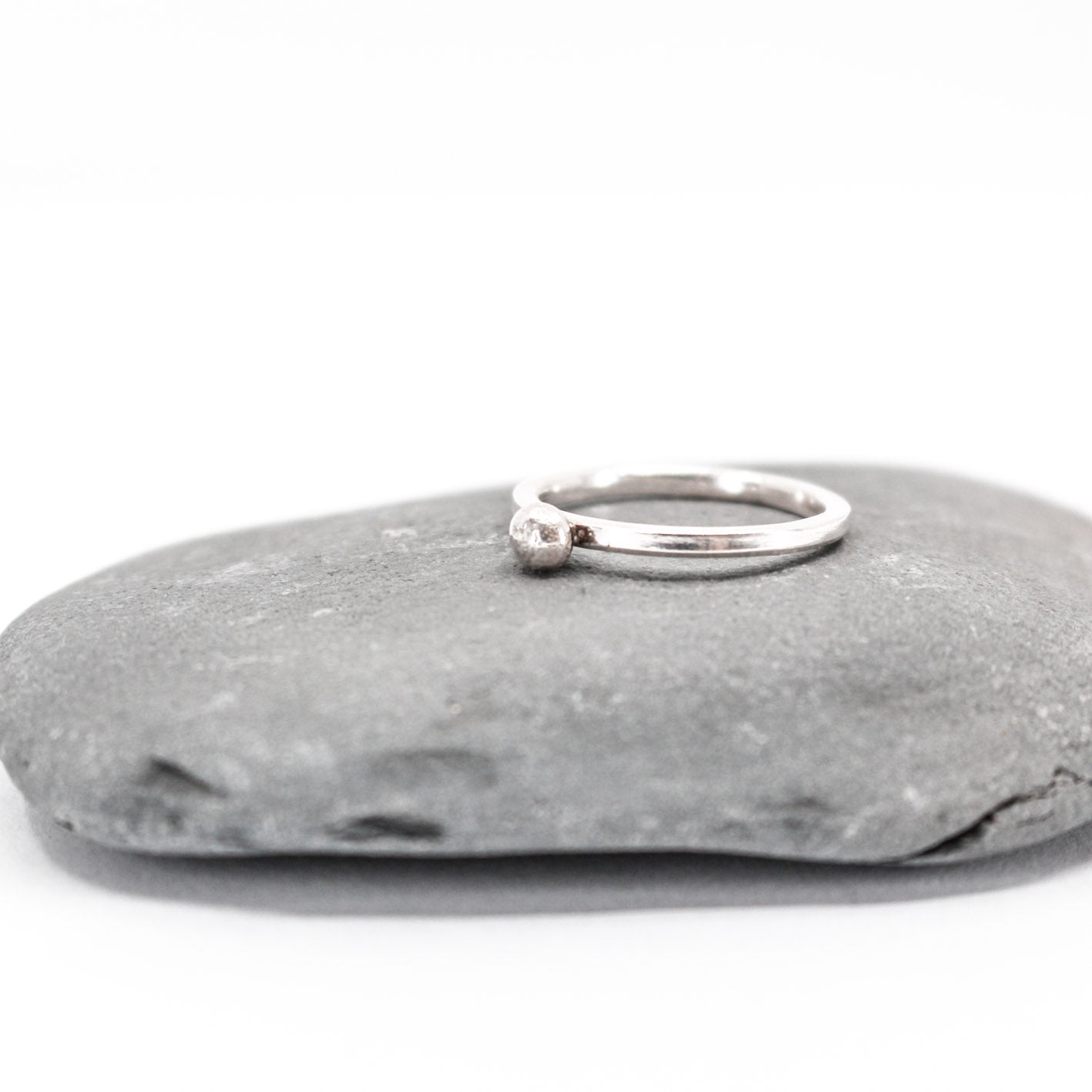 five simple silver stacking rings each with a textured sterling silver drop