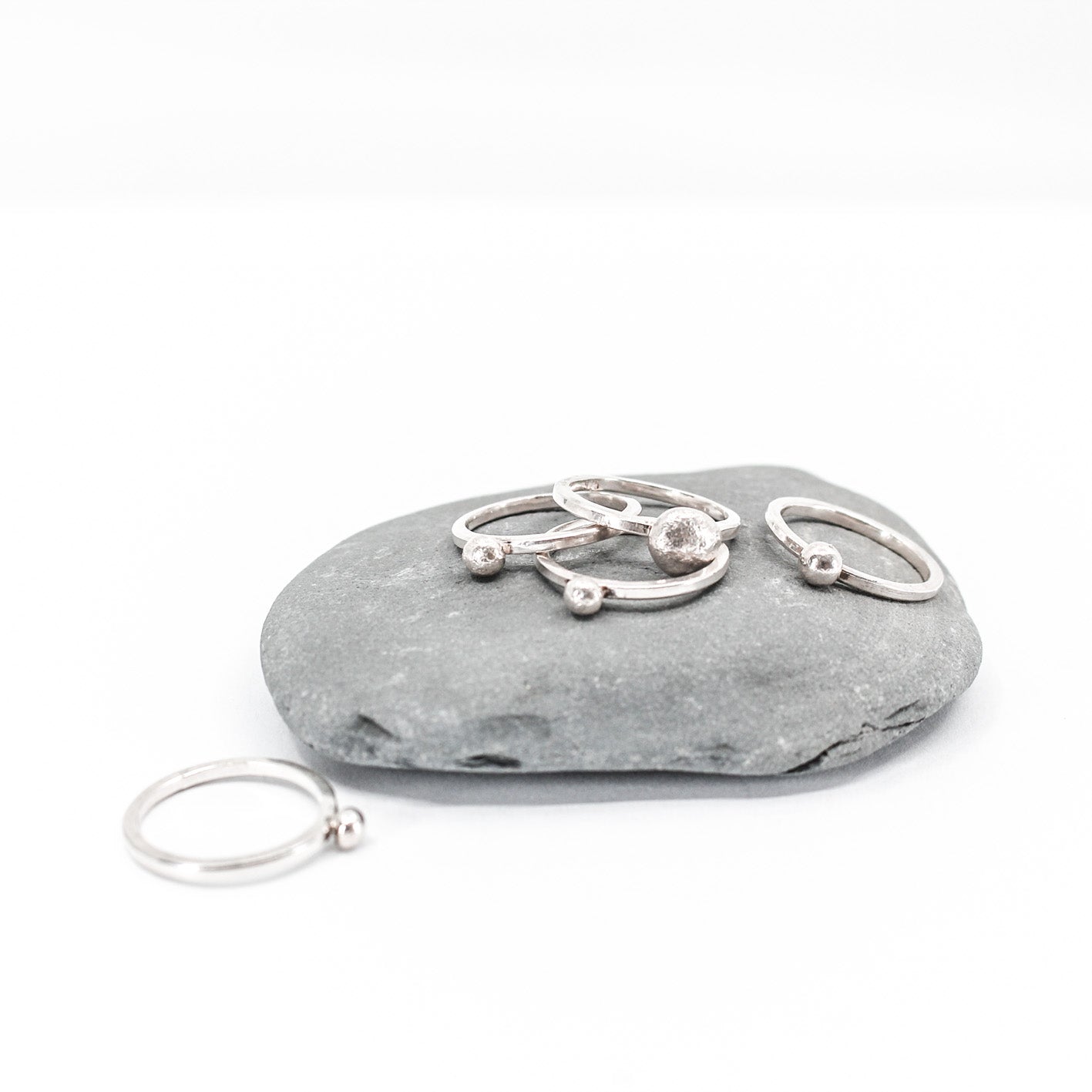 five simple silver stacking rings each with a textured sterling silver drop