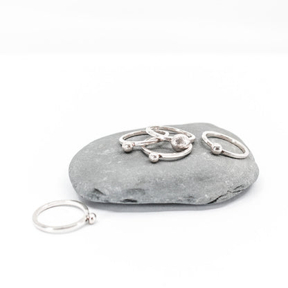 five simple silver stacking rings each with a textured sterling silver drop