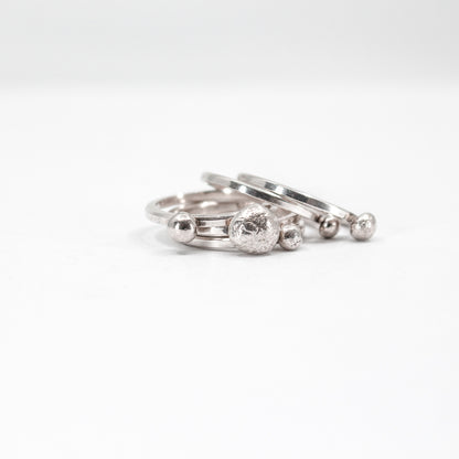 five simple silver stacking rings each with a textured sterling silver drop