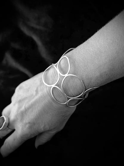 Woman wearing one-of-a-kind sculptural sterling silver cuff bangle, black and white styled photo