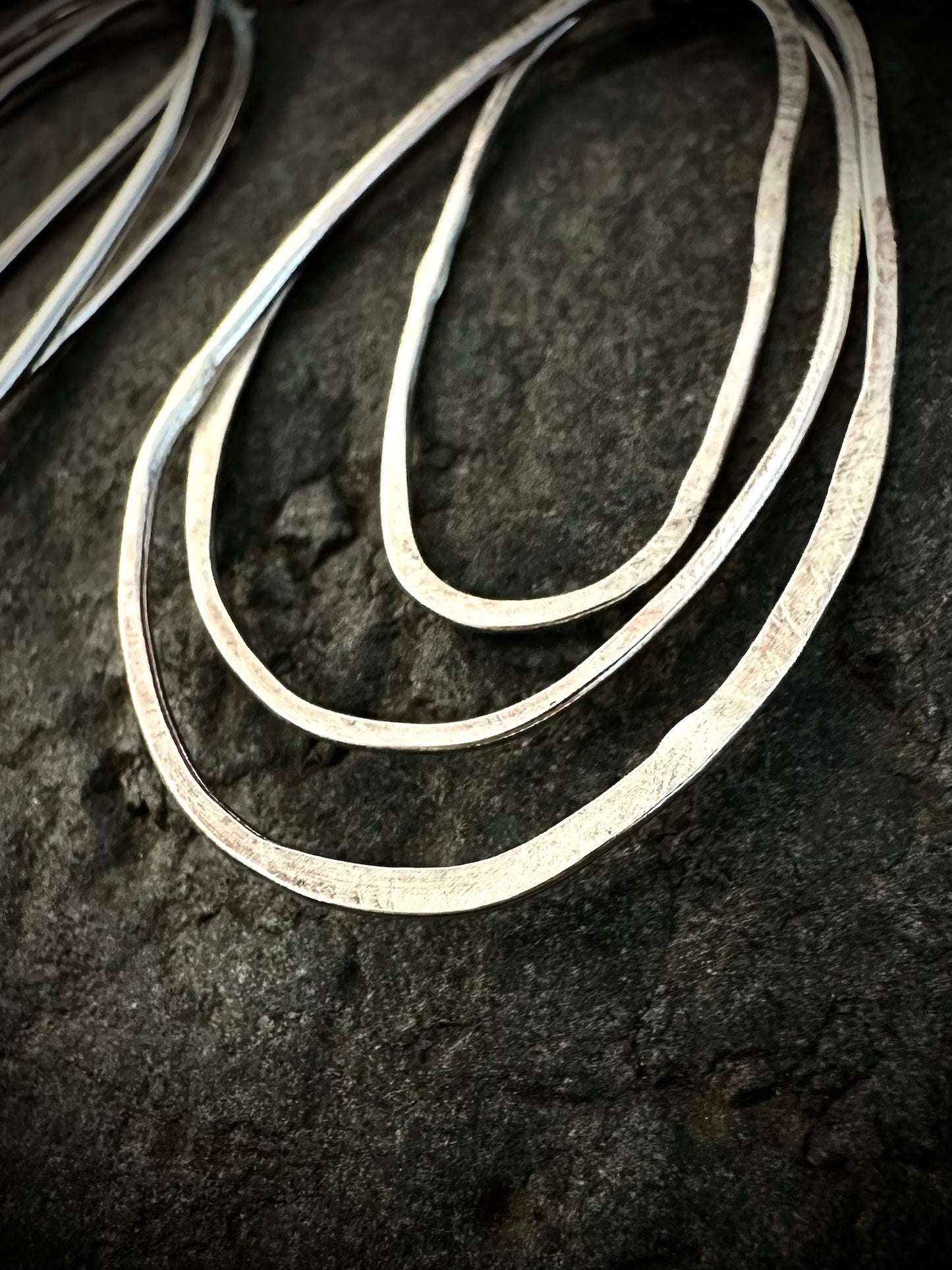 Large sculptural silver hoop earrings on stone - three-loop organic design