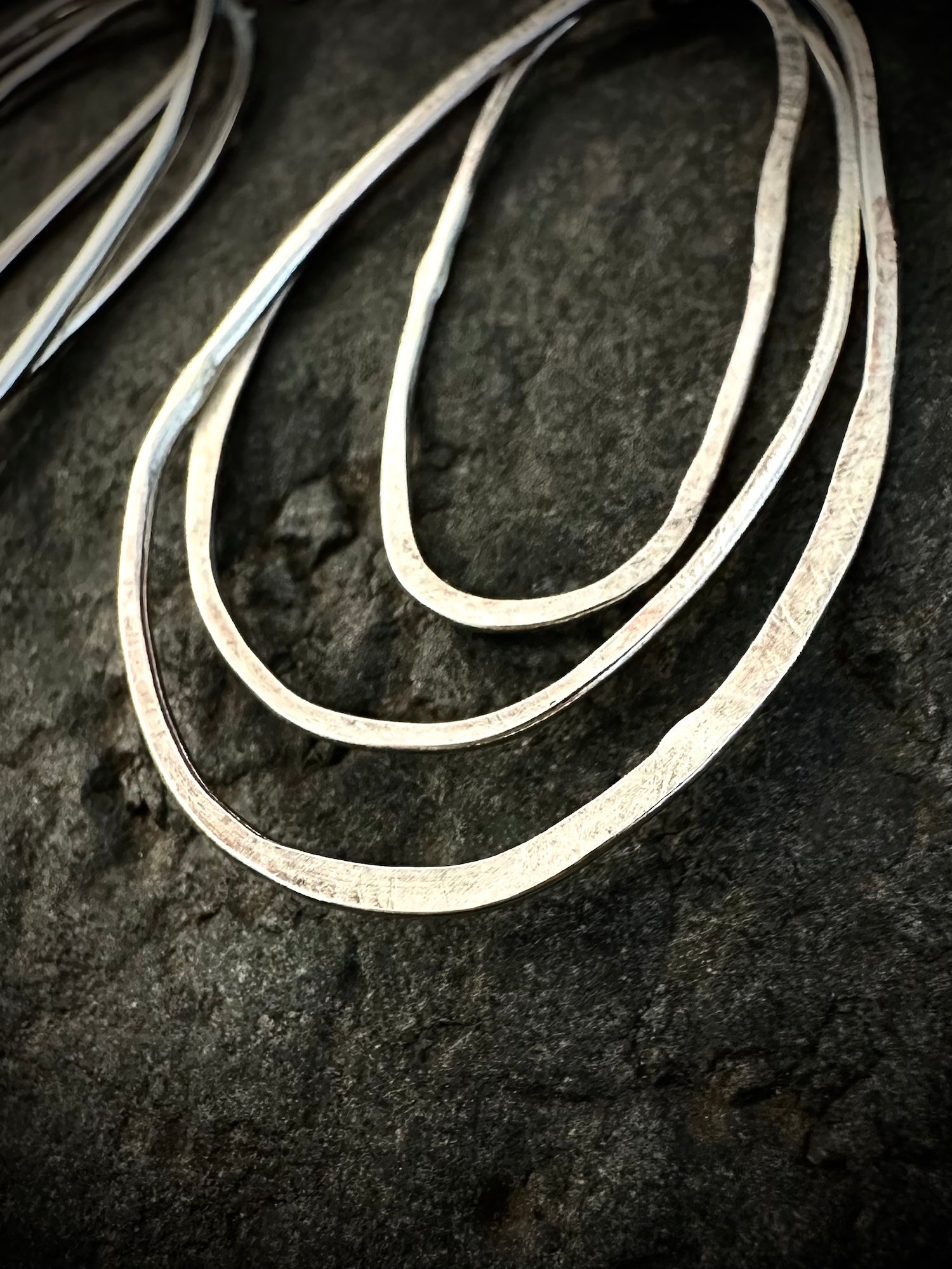Large sculptural silver hoop earrings on stone - three-loop organic design