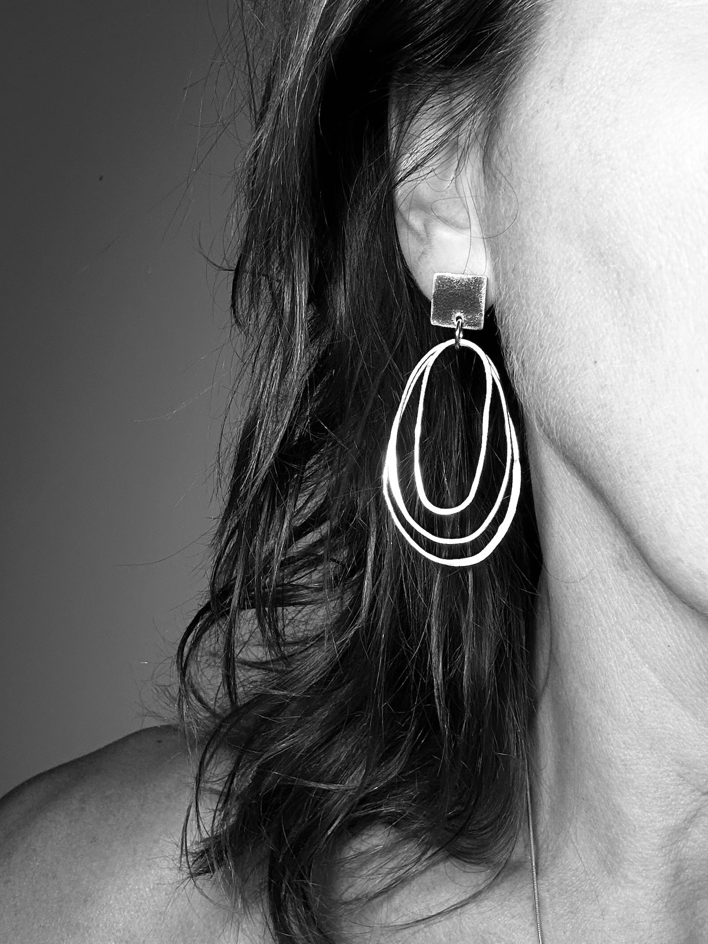 Woman wearing sculptural silver hoop earring with resin accent - side profile