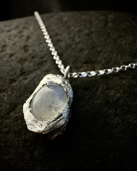 Close-up of sterling silver nugget pendant set with oval moonstone showing soft blue shimmer 