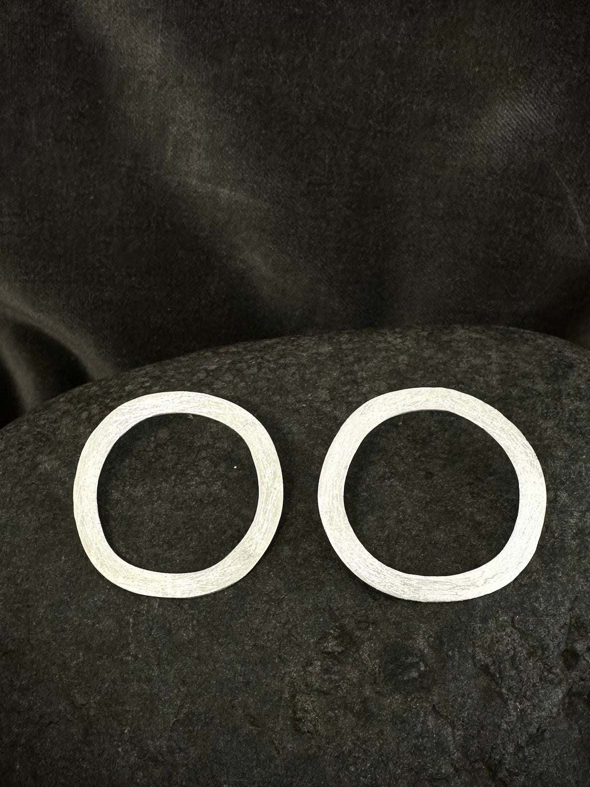 Flat lay of sterling silver circle hoop earrings, hammered and textured, approx 35mm diameter