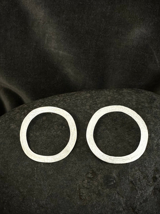 Flat lay of sterling silver circle hoop earrings, hammered and textured, approx 35mm diameter