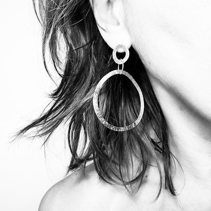 Woman wearing textured silver hoop earring - hammered drop hoop
